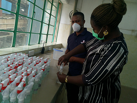 Amalunweze and a colleague prepare sanitizer for distribution to prevent the spread of COVID-19.