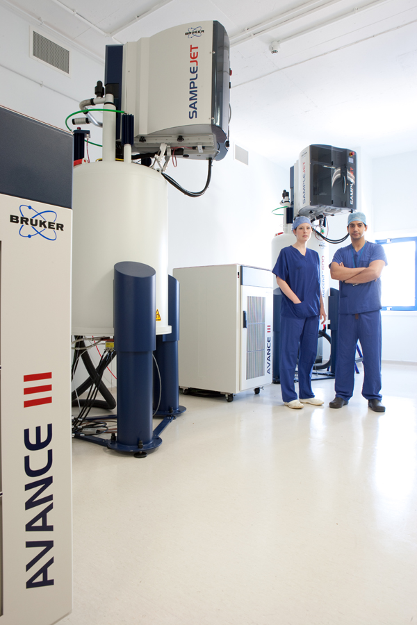 Photo of two surgeons standing next to two of the new 600 MHz NMR spectrometers