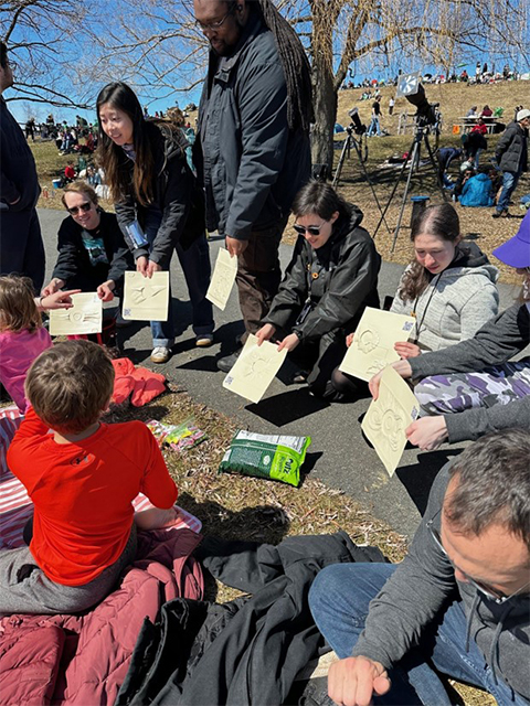 Five Landmark College students play an accessible game with lithographs depicting past eclipses provided by the NASA PUNCH Outreach program.