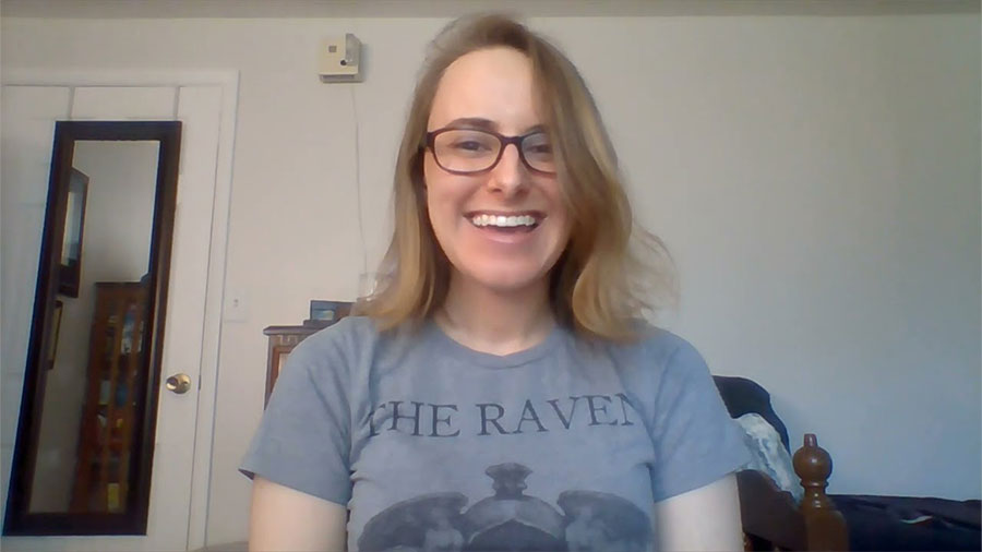 Megan Lengel, a young white person with light brown hair and glasses, smiles at the camera during a YouTube video presentation for the Usher community.