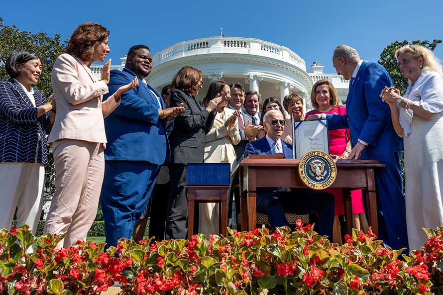 Surrounded by lawmakers, President Biden signs the CHIPS and Science Act on Aug. 9 at the White House.
