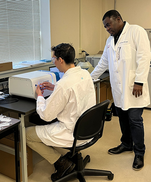 John Mullins, an ASBMB Student Chapter member, works on the OpenSPR instrument in the lab as Tayo Odunuga looks on.