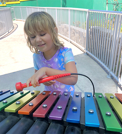 Coral, who suffers Dup15q syndrome, from plays with a xylophone outdoors in 2023. Coral and her family participate in research studies with the Dup15q Alliance, a patient advocacy organization for patients with at least one extra chromosome 15 region, 15q11.2 – 13.1.