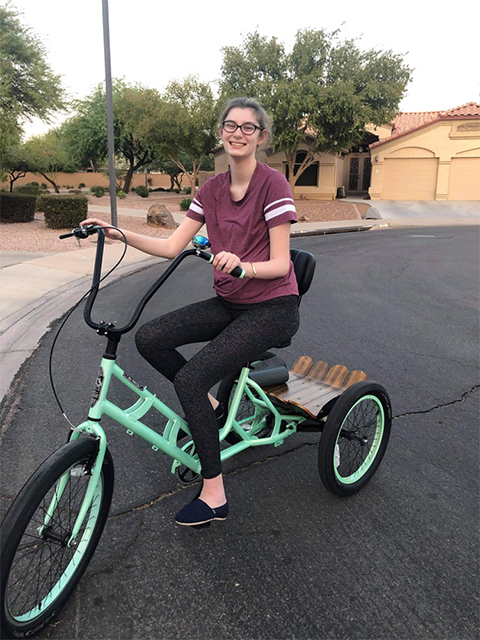 Anissa Merriam, who suffers from Lafora disease, enjoys a bike ride outdoors on a utility trike, which offers extra stability for those with motility challenges.