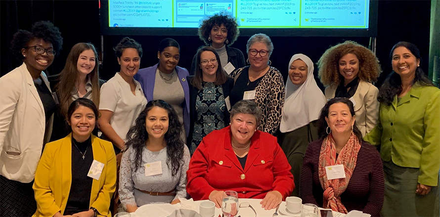 Carlota Ocampo (seated at right with scarf) and Trinity President Patricia McGuire (in red in center) with students and other staff at a Washington Women’s Foundation event.