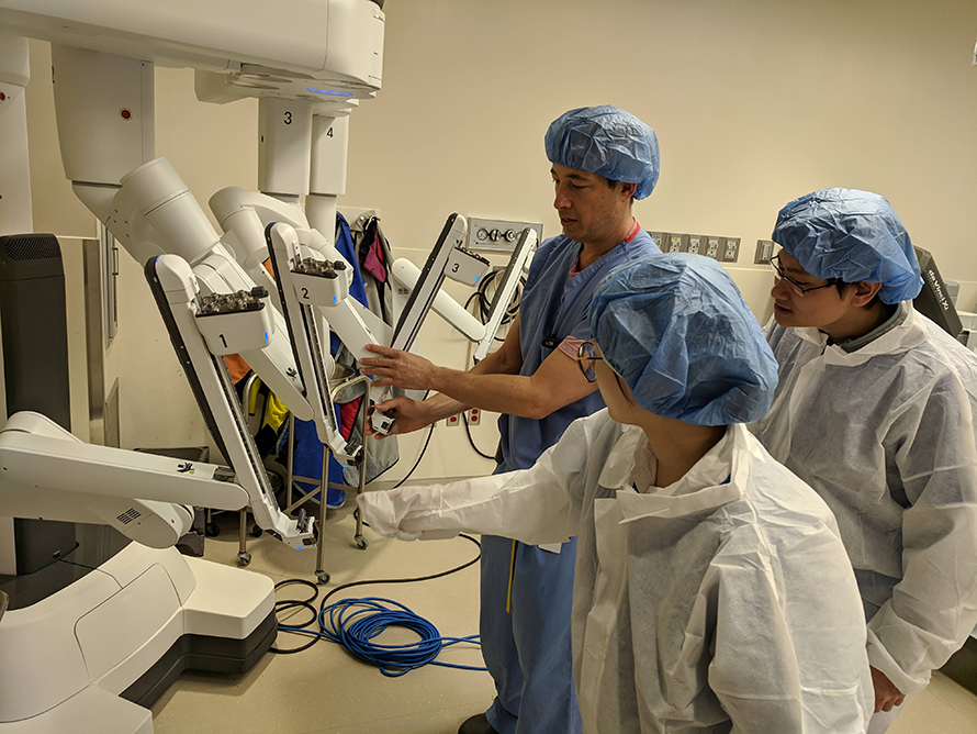 Ronald Boris explains the dynamics of the robotic patient cart, which holds the camera and instruments that the surgeon controls from the robotic console used for kidney tumor removal, to Purdue graduate students Peipei Zhu and Marco Hadisurya in the surgical room.