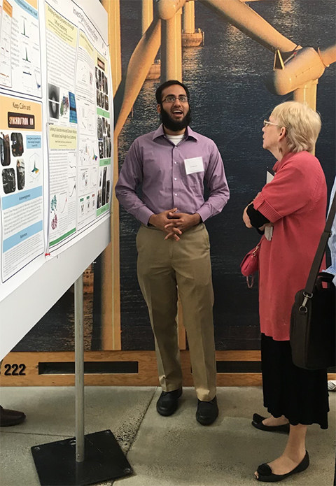 JoAnne Stubbe, carrying her signature pad of paper, talks to a student during a poster session at a meeting at the Massachusetts Institute of Technology, where she is a professor emerita of chemistry.