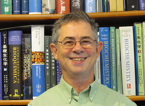 Donald Voet in front of shelves of biochemistry textbooks