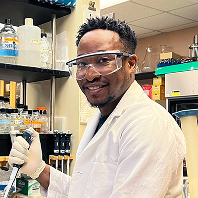 Portrait of Sam Shobade pipetting in a lab