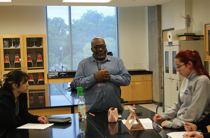 Aubrey Smith, biology professor at Montgomery College in Rockville, Maryland, center, checks in with students Kyra McDonald, left, and Diana Urtecho Alvarado, right, as they complete an in-class exercise in May 2023.