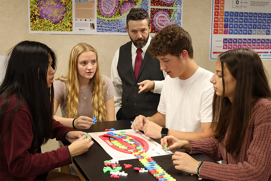 Mark Arnholt, a high school teacher turned SMART Team coordinator, center, looks on as students at Cedarburg High School use 3D Molecular Design’s Flow of Genetic Information Kit.